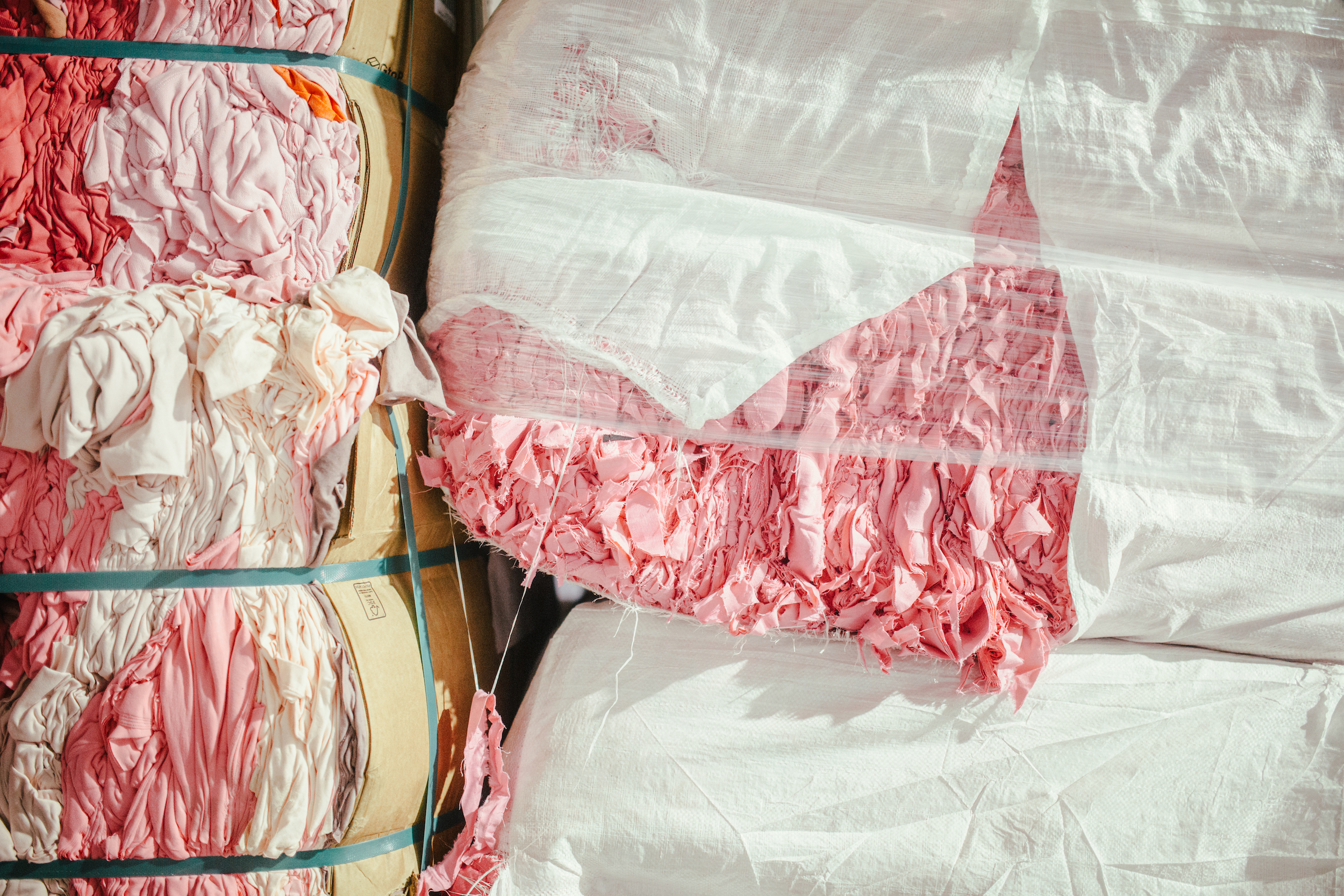 Fardos de residuos textiles rosas reciclados en la planta de Coleo para su reutilización circular
